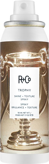 En sprayflaska märkt R+Co Trophy Shine Texture Spray, med en tydlig bild av ett trofé på etiketten.