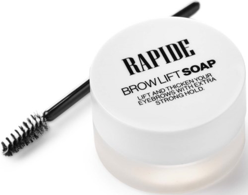 Een witte pot met het label RAPIDE Brow Lift Soap en een wenkbrauwborstel op een witte achtergrond.