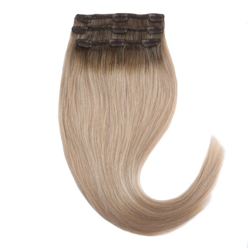 Hårförlängningar i blont med mörka rötter, stylade i en lockig, glänsande stil.