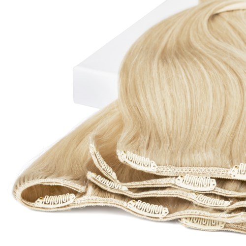 En blond peruk på en vit yta, med ett band eller band längst ner.