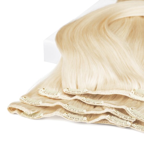 En blonder peruk ovanpå tre beige hårnät eller mössor, ordnade i rad.