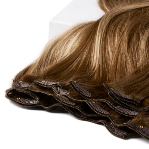 Een pruik of haarstuk op een lichte ondergrond, met lange, bruin haar en een glanzende, getextureerde basis.