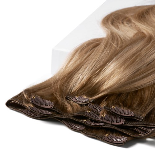 Welliges blondes Haar liegt flach auf einer Oberfläche neben einer weißen Box.