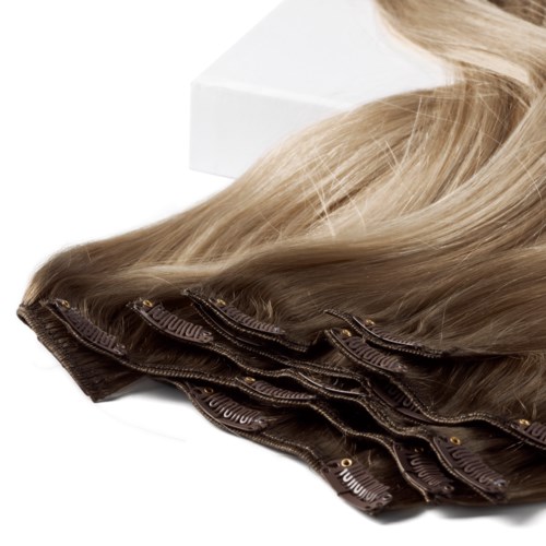 Stapel blond haarextensions of wimpers met clips op een witte ondergrond.