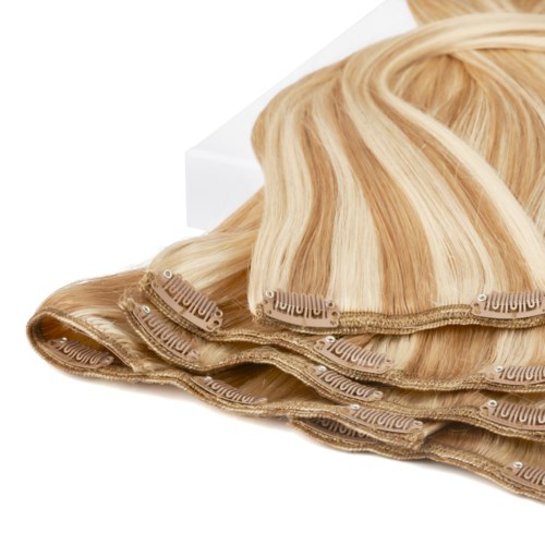 En blond lace front-peruk med flera vävstrån, delvis lockad, på en vit yta.