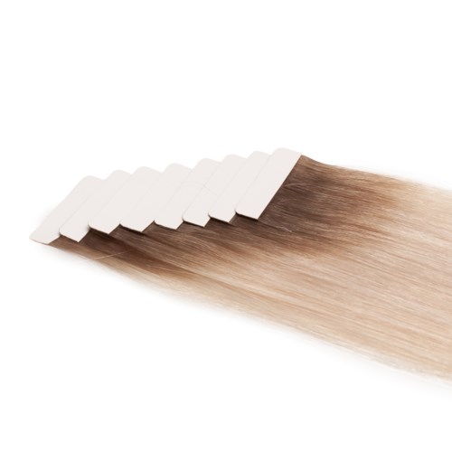 Flera hårförlängningar är fästa vid en vit remsa och visar en gradient från mörkare till ljusare blond. Mycket slätt hår.