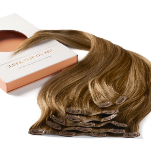 Ein Set Haarspangen mit langen, welligen, hellbraunen Haarverlängerungen und eine Box mit der Aufschrift 'Sleek Clip On Set.'
