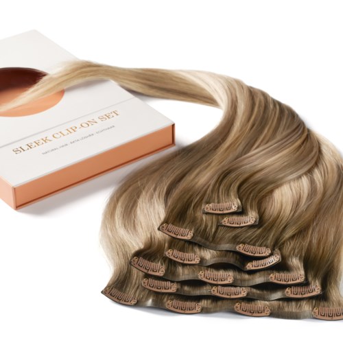 Haarverlängerungen in einer Schachtel mit Clips, gestapelt, hellblonde Farbe. Die Schachtel trägt den Schriftzug "Sleek Clip On Set."
