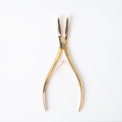 Een goudkleurige nagelriemknipper op een witte achtergrond.