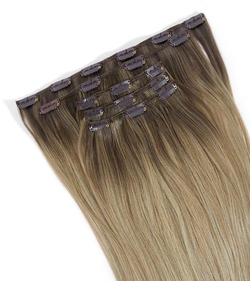 Mehrere Haarverlängerungen mit Clips, hellbraun oben, verblassend zu blond an den Enden.