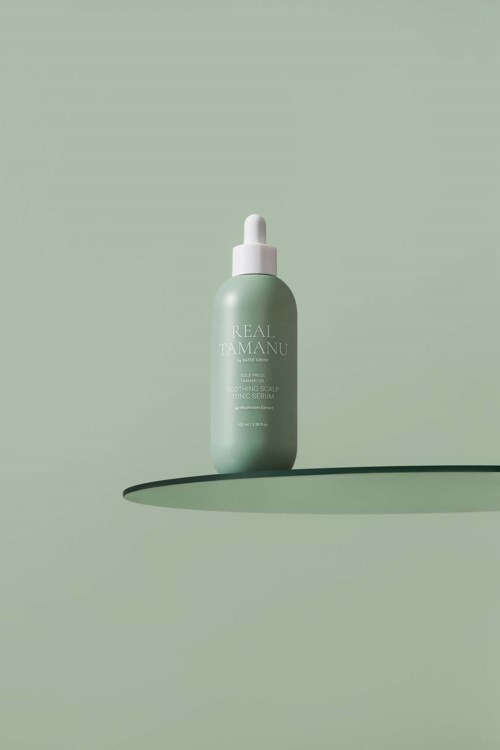Een groene huidverzorgingsfles met pipet ligt op een bijpassende groene achtergrond en werpt een schaduw.