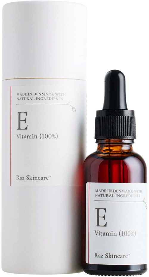 En liten bärnstensfärgad glasflaska med pipett, märkt E Vitamin, bredvid en lång vit behållare från Raz Skincare.