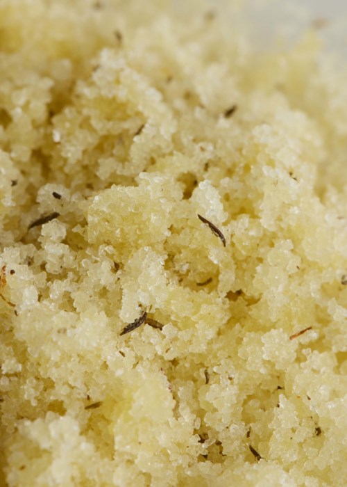 Finmalat gul substans med små svarta partiklar som liknar matrester eller granular material.
