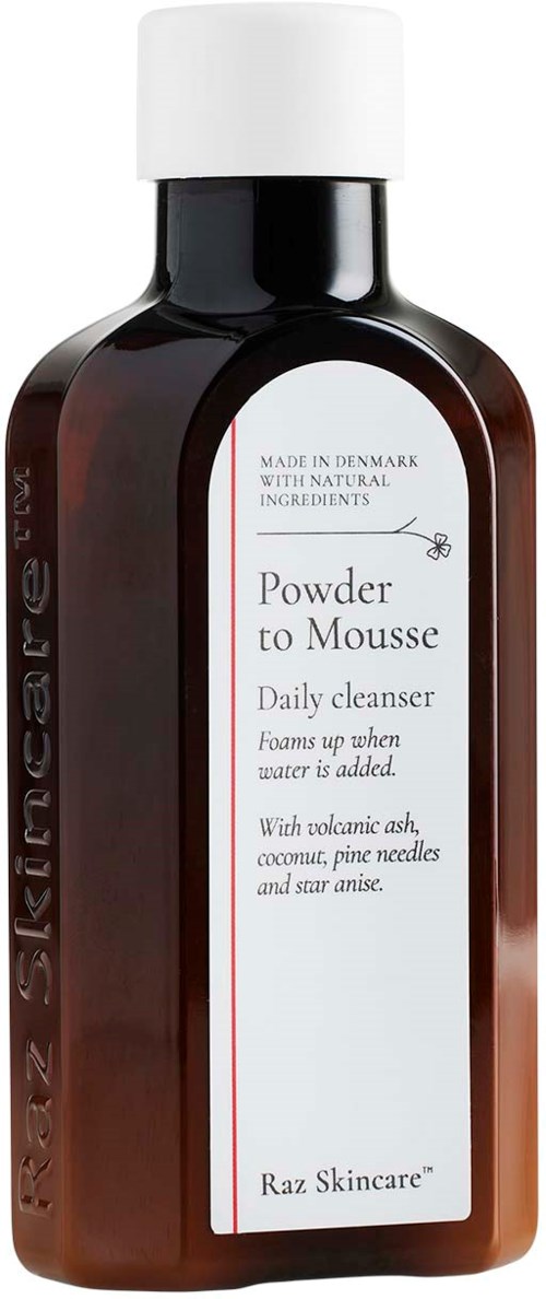 En flaska märkt 'Powder to Mousse Daily cleanser' med vit lock, mörkbrunt kropp, och vit frontetikett med röd text.