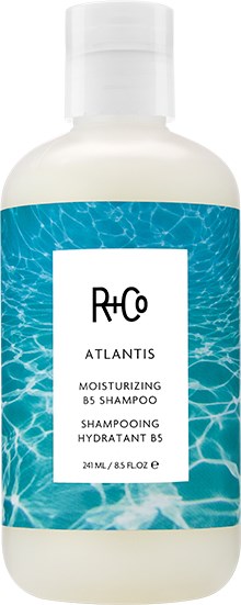 Een wit flesje met een blauw label met waterpatroon, gemarkeerd als hydraterende shampoo door Rico Atlantis.