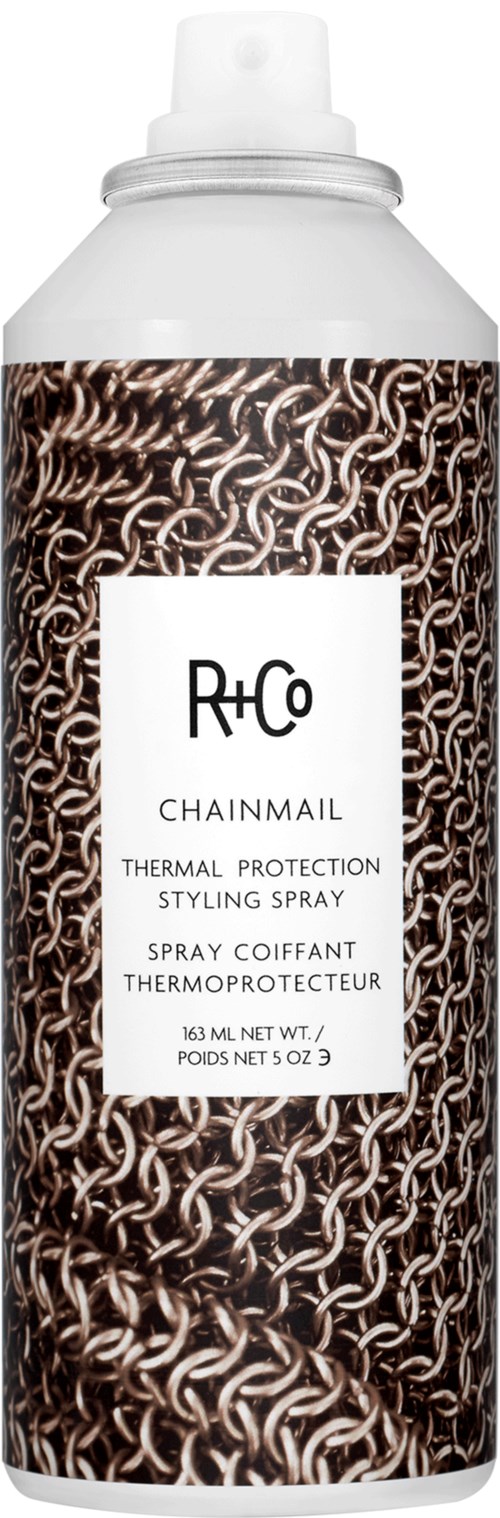 Een witte fles met een kettingpatroon op het etiket, genaamd R+Co Chainmail, een hittebeschermende styling spray.