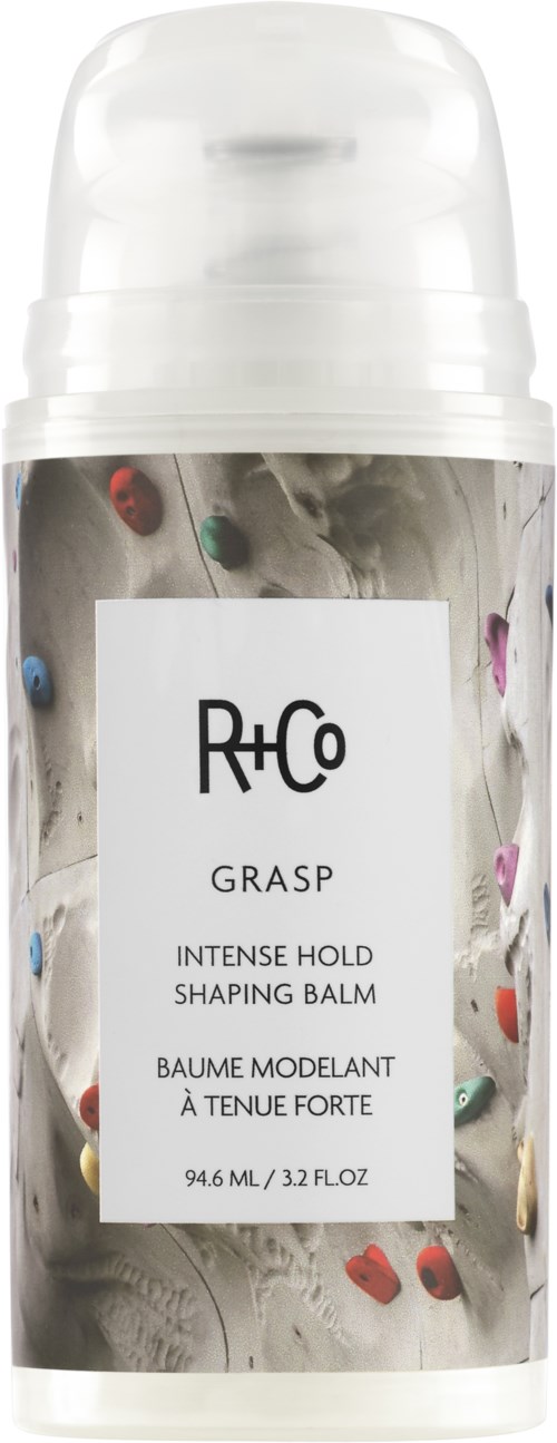 Witte fles met R+Co Grasp stylingbalsem met kleurrijke klimrekjes op het label.