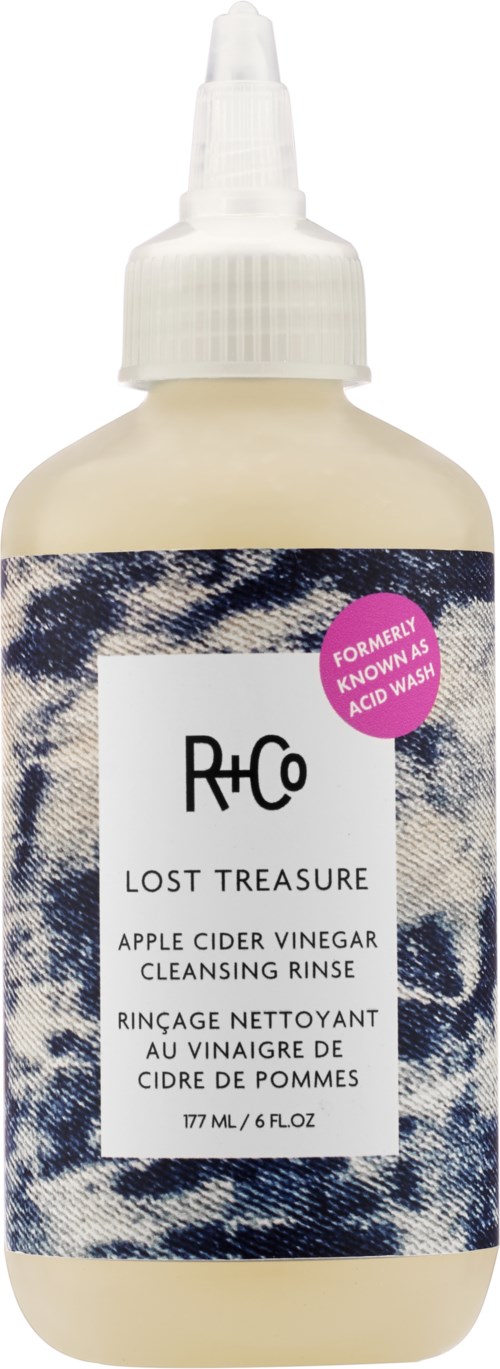 Een beige fles met een witte spraydop, met label "Lost Treasure" appelciderazijnspoeling.