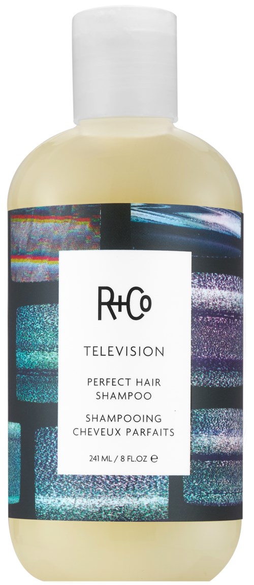 Een fles R+Co TVH shampoo met een kleurrijk, abstract labelontwerp en witte dop.