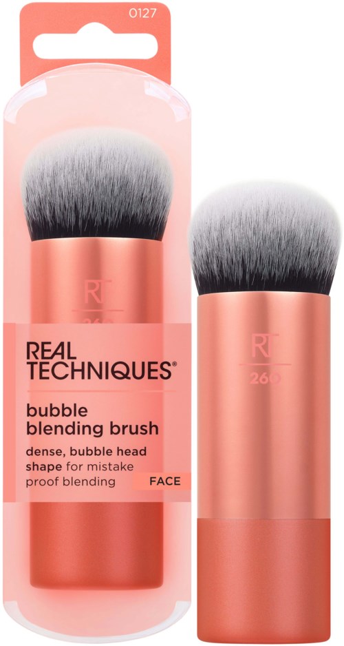 A makeup brush in a pink and black gradient color, with packaging showing the brand Real Techniques and product details.