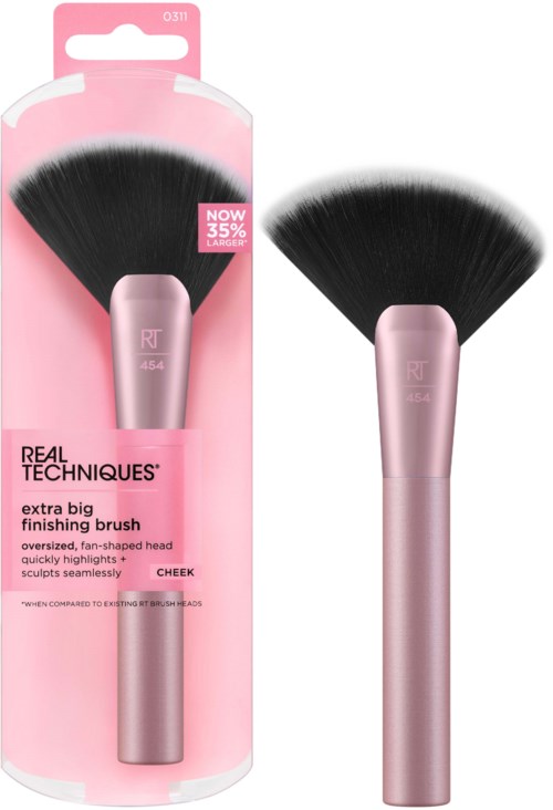 A makeup brush with a pink handle and large black fan-shaped bristles, standing vertically outside packaging.