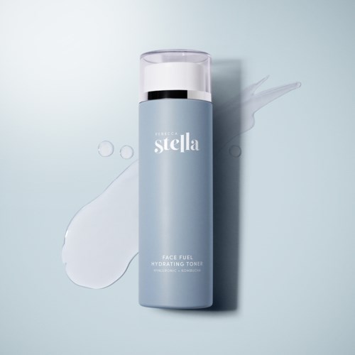 A light blue bottle of face toner with the brand name Stella, showing liquid spill on a light background.