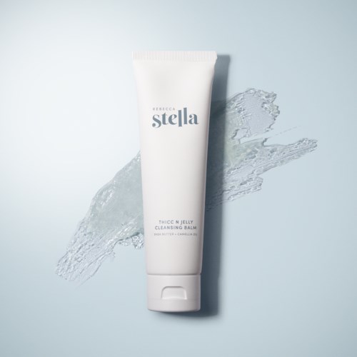 A white tube labeled 'stella', with water splashed behind it, on a light background.