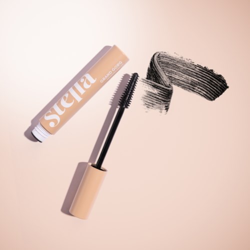 A beige tube of mascara with wand, smudged black mascara on surface, and the brand name 'Sierra' on tube.