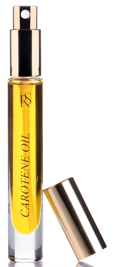 En lång, klar glasflaska med gul olja inuti och metallock, märkt 'Carotene Oil'.