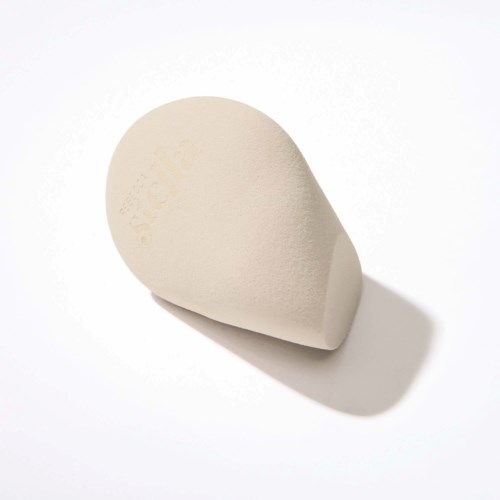 A white beauty blender sponge with a semi-rough texture and shadow on a white background.