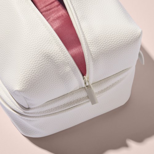 A white textured bag with a zipper and a hint of pink inside. The bag is close-up and shows part of the top.
