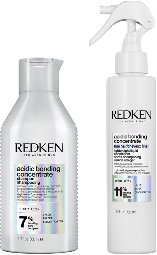 Two white bottles of Redken hair products, one shampoo and one conditioner, have black and blue labels and spray nozzle.