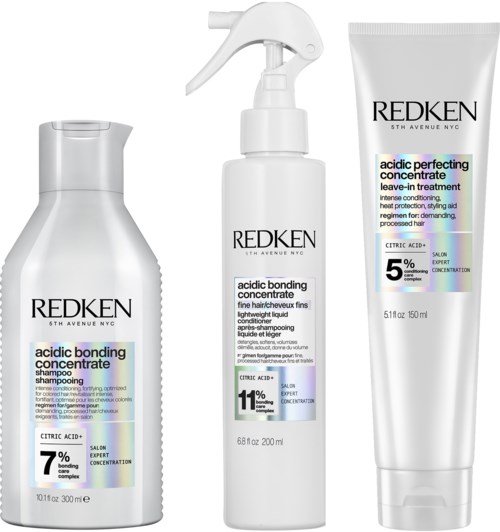 Three Redken hair care products: shampoo, leave-in treatment, and conditioner, each with different citric acid concentrations.