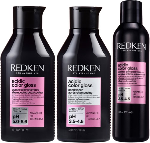 Drie zwarte flessen Redken zure smaakglans haarproducten staan samen. Ze bevatten shampoo, conditioner en glans behandeling.