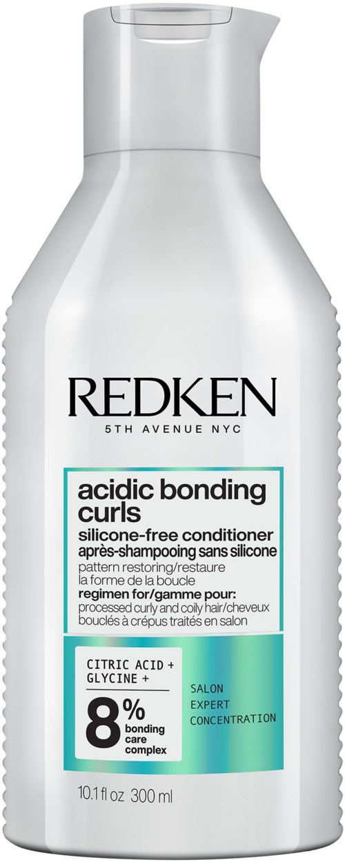 Een wit flesje Redken-shampoo voor krullend haar met teal en zwarte tekst, benadrukt zuurgraad en binding.