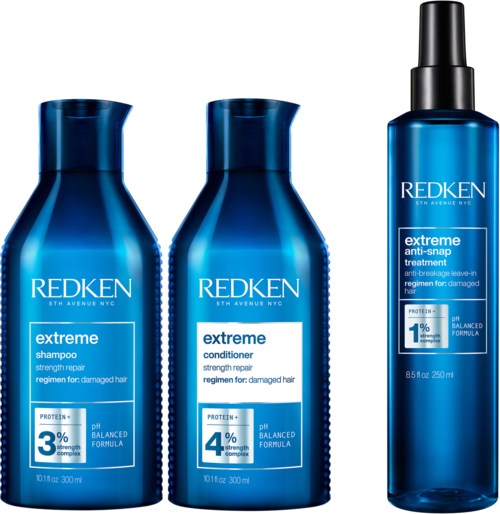 Drie blauwe flessen Redken haarverzorgingsproducten: shampoo, conditioner en spray, voor beschadigd haarherstel.