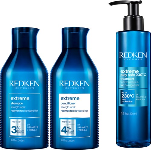 Drie haarverzorgingsflessen van Redken, twee voor shampoo en conditioner, en één voor behandeling, allemaal in blauwe flessen.