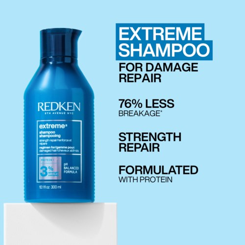 Blauwe shampoefles op een witte oppervlakte, met tekst over beschadigingsherstel en kracht van Redken.