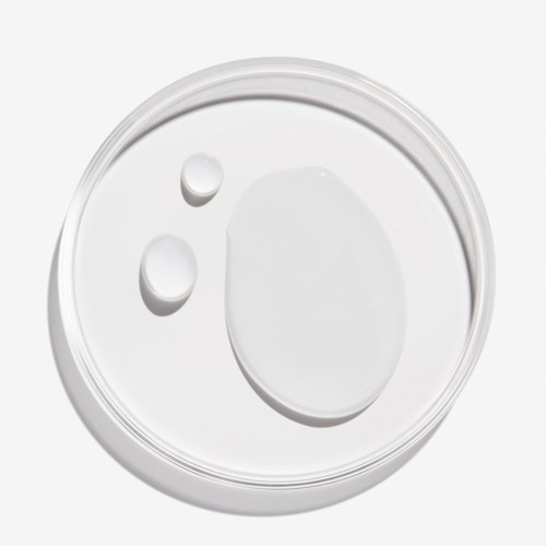 Drie druppels witte vloeistof op een doorzichtige glazen plaat, met een grote ovale en twee kleinere ronde druppels.