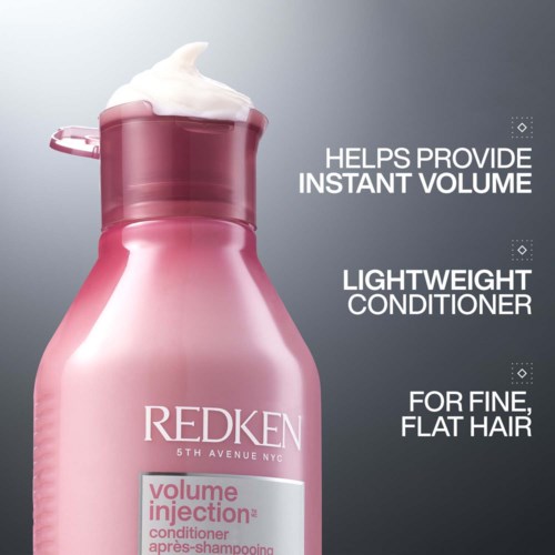 Roze fles van Redken volume conditioner met schuim erop, beweert volume te geven voor fijn, plat haar.