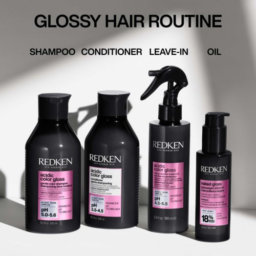 Een zwarte fles Redken haar gloss met roze label, die glans, gevoel en hittebescherming biedt tot 230°C.