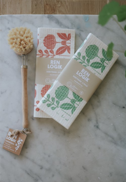 Two boxes of skincare products with floral designs, a natural brush, and a small tag on a marble surface.