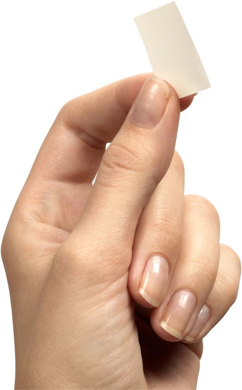 Een hand houdt een klein wit leeg kaartje vast tussen duim en vinger.