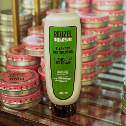 Reuzel Rosemary Mint dry shampoo bottle displayed among pink containers on a shelf.