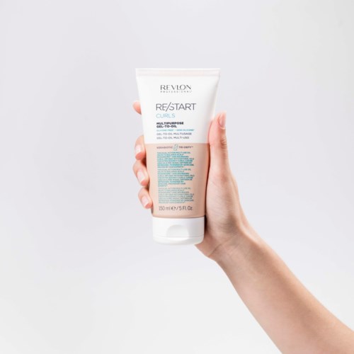 Eine Hand hält eine Revlon-Haarpflegeprodukt-Tube vor einem hellen Hintergrund.