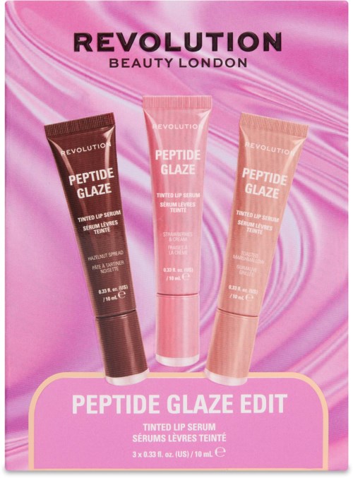 Tre rør av Revolution Peptide Glaze farget leppe serum i rosa, beige og mørk brun på rosa bakgrunn.