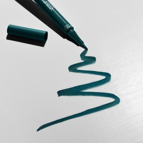 A teal marker draws a zig-zag line on white paper, with the cap off and nearby.