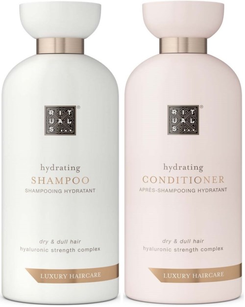 Two bottles, one white and one pink, labeled as hydrating shampoo and conditioner for dry hair with hyaluronic complex.