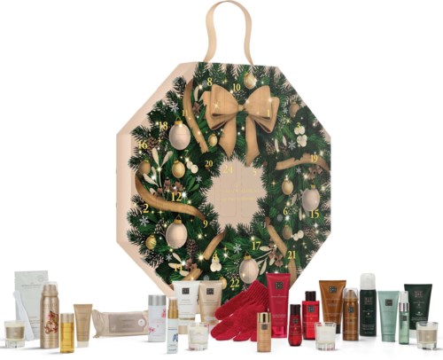 Goldene Schleife, grüner Adventskranz mit Tannenzapfen, goldene und weiße Ornamente, rote Handschuhe und verschiedene Hautpflegeprodukte.