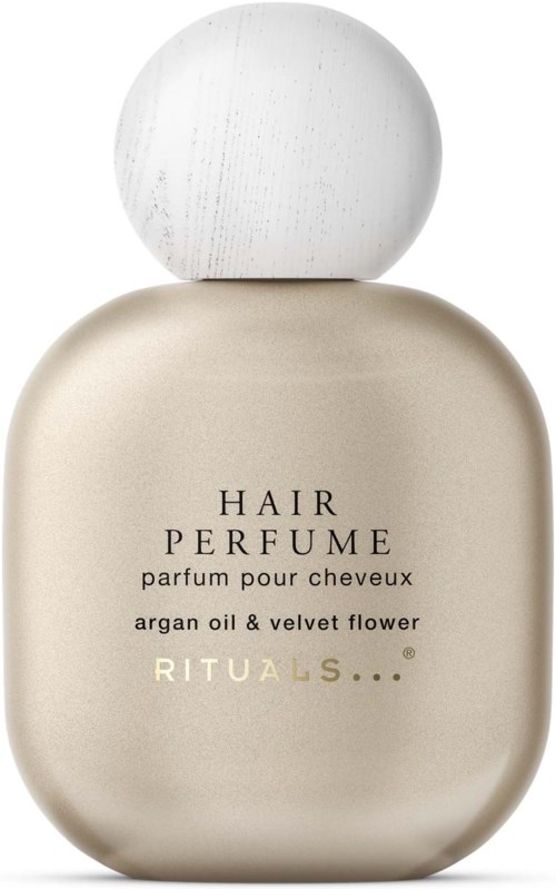 A perfume bottle with a white spherical cap and a cream-colored body, labeled 'Hair Perfume' with argan oil and velvet flower.